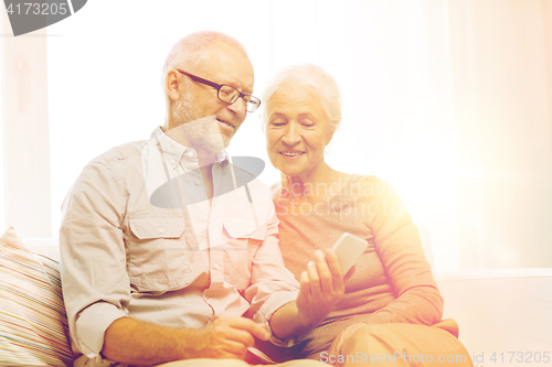 Image of happy senior couple with smartphone at home