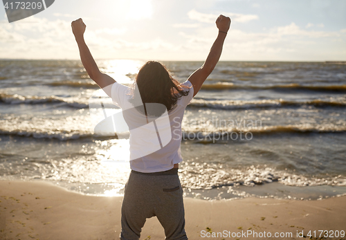 Image of man with rised fist on beach