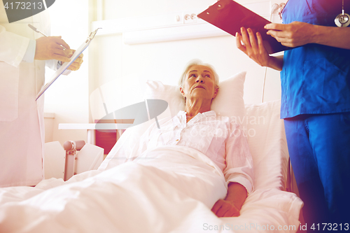 Image of doctor and nurse visiting senior woman at hospital