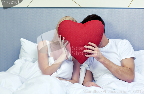 Image of happy couple in bed with red heart shape pillow