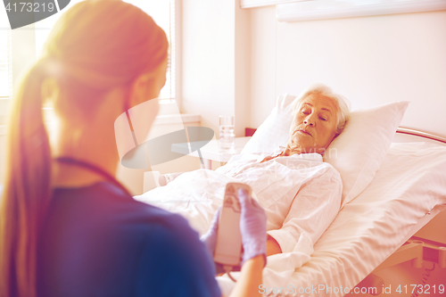 Image of doctor or nurse visiting senior woman at hospital