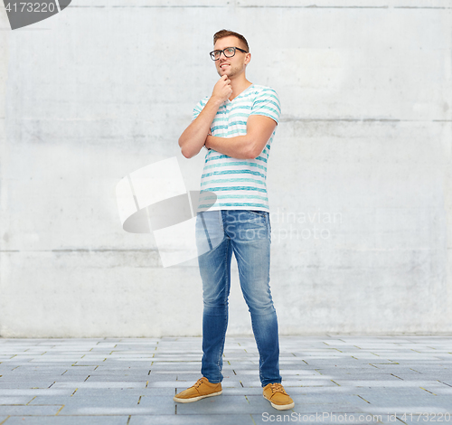 Image of smiling young man in eyeglasses thinking