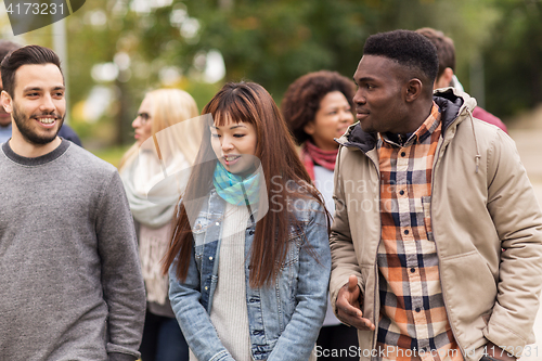 Image of happy friends walking along autumn park