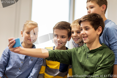 Image of group of happy kids taking selfie with smartphone
