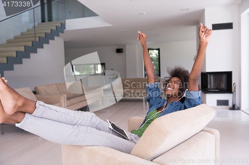 Image of African american woman at home in chair with tablet and head pho