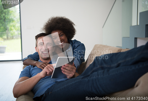 Image of multiethnic couple relaxing at  home with tablet computers