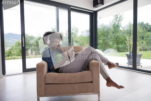 Image of African american woman at home in chair with tablet and head pho