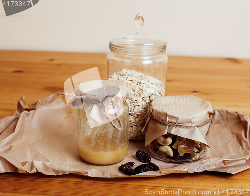 Image of real comfort wooden kitchen with breakfast ingredients close up in glass, honey, oatmeal, milk, muesli, morning food