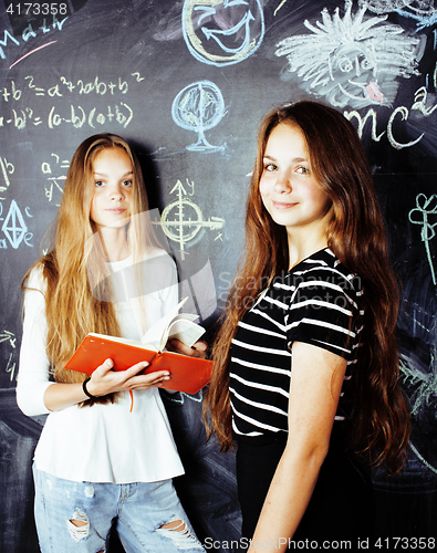 Image of back to school after summer vacations, two teen real girls in classroom with blackboard painted together