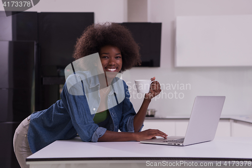 Image of smiling black woman in modern kitchen