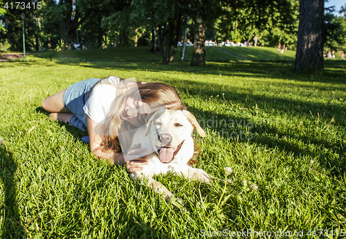 Image of young attractive blond woman playing with her dog in green park at summer, lifestyle people concept