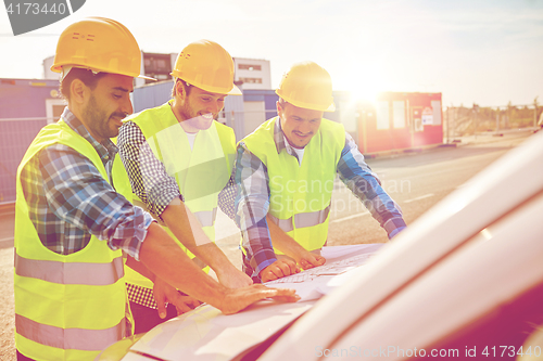 Image of close up of builders with blueprint on car hood