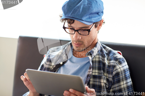 Image of man with tablet pc sitting at cafe table