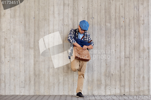 Image of hipster man looking for something in his bag