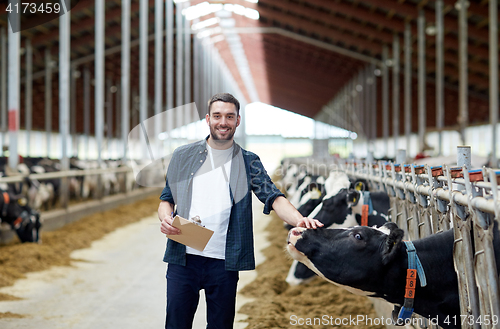 Image of farmer with clipboard and cows in cowshed on farm