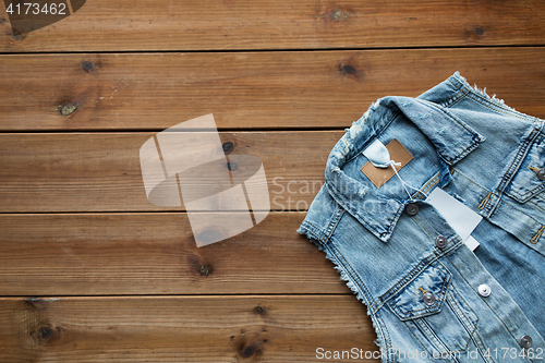 Image of close up of denim waistcoat with price tag on wood