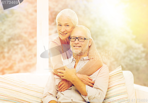 Image of happy senior couple hugging on sofa