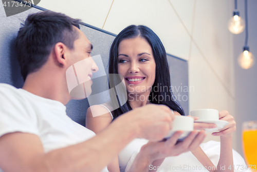 Image of smiling couple having breakfast in bed in hotel