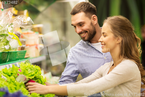 Image of happy couple buying lettuce at grocery store