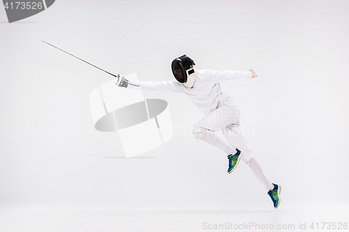 Image of Man wearing fencing suit practicing with sword against gray