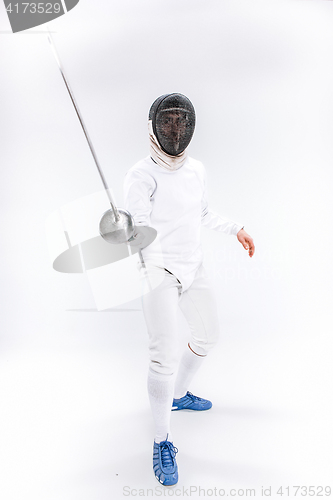 Image of Man wearing fencing suit practicing with sword against gray