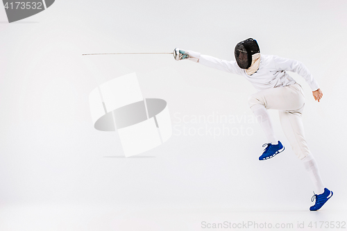 Image of Man wearing fencing suit practicing with sword against gray