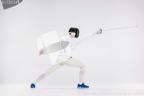 Image of Man wearing fencing suit practicing with sword against gray