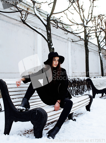 Image of young pretty modern hipster girl waiting on bench at winter snow park alone, lifestyle people concept 