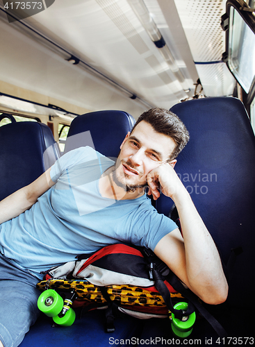 Image of young pretty modern hipster guy traveller on train with skateboa