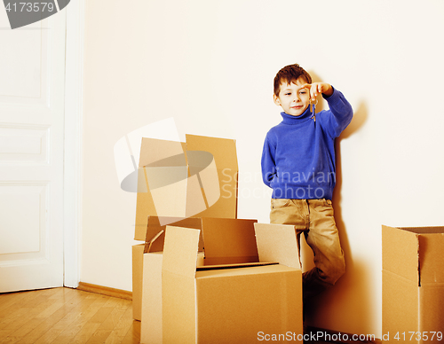 Image of little cute boy in empty room, remoove to new house. home alone emong boxes close up kid smiling