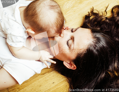 Image of young brunette happy mother holding toddler baby son, breast-fee