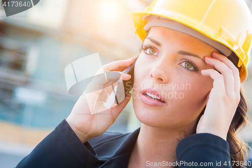 Image of Worried Female Contractor Wearing Hard Hat on Site Using Cell Ph