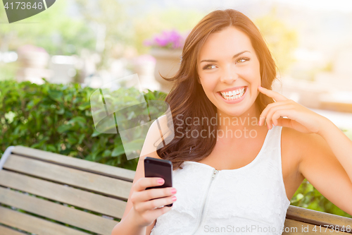 Image of Smiling Young Adult Female Texting on Cell Phone Outdoors