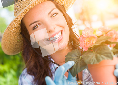 Image of Young Adult Woman Wearing Hat and Gloves Gardening Outdoors