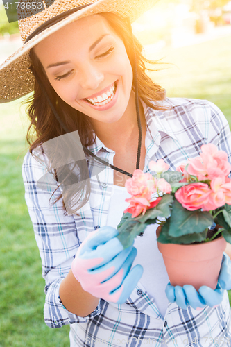 Image of Young Adult Woman Wearing Hat and Gloves Gardening Outdoors