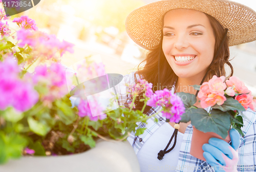 Image of Young Adult Woman Wearing Hat and Gloves Gardening Outdoors