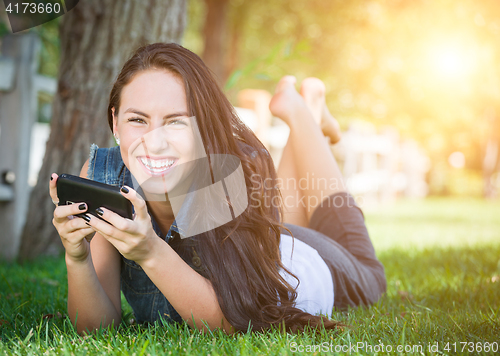 Image of Mixed Race Young Female Texting on Cell Phone Outside In The Gra