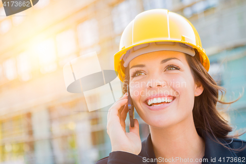 Image of Young Female Contractor Wearing Hard Hat on Site Using Phone