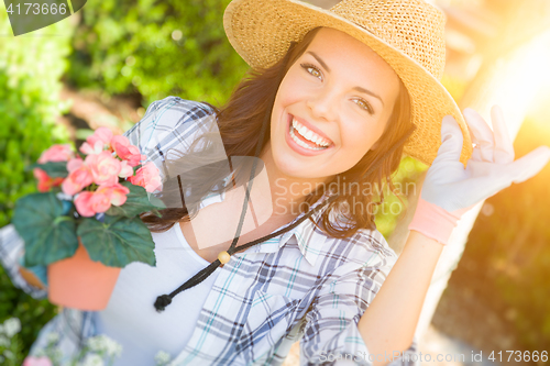 Image of Young Adult Woman Wearing Hat and Gloves Gardening Outdoors