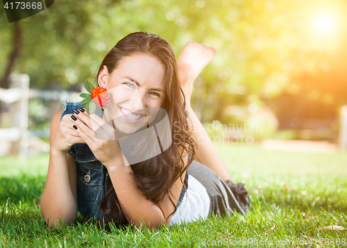 Image of Attractive Mixed Race Girl Holding Flower Portrait Laying in Gra