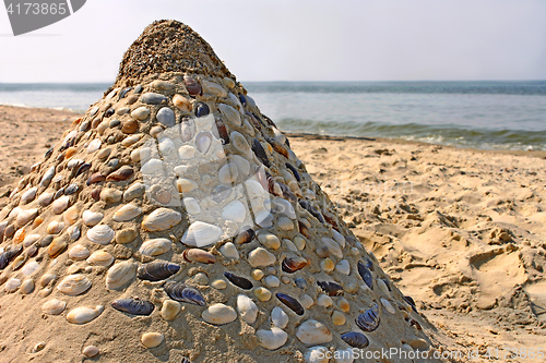 Image of Sandy pyramid with shells on a sea beach