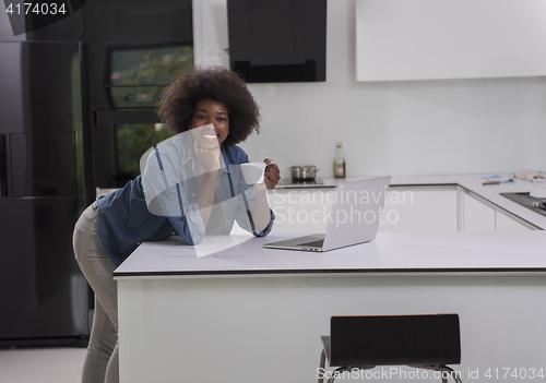 Image of smiling black woman in modern kitchen