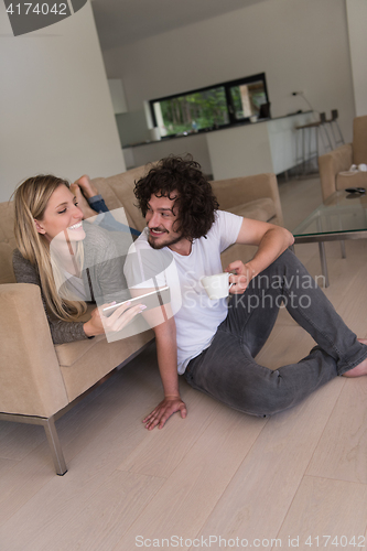 Image of couple relaxing at  home with tablet computers