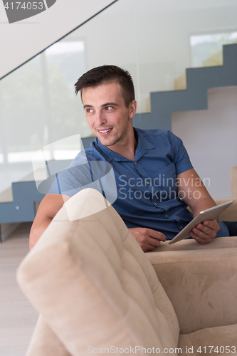 Image of young man using a tablet at home