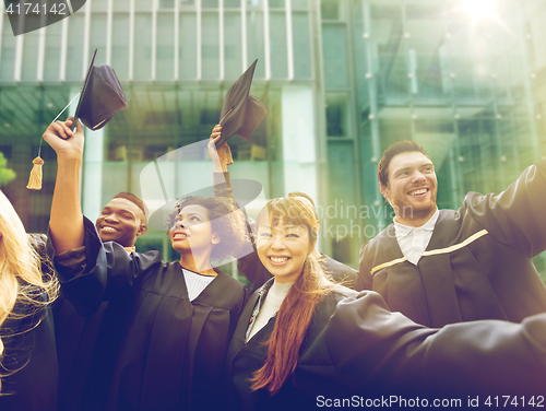 Image of happy students or bachelors waving mortar boards