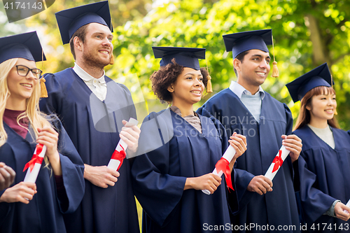 Image of happy students in mortar boards with diplomas