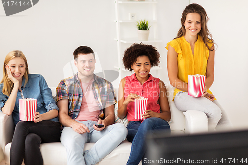 Image of happy friends with popcorn watching tv at home