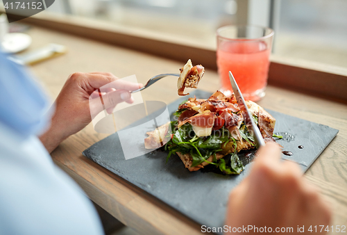 Image of woman eating prosciutto ham salad at restaurant