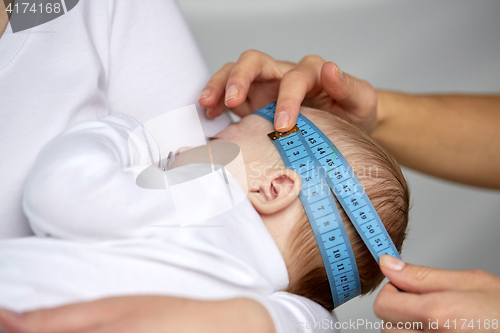 Image of close up of hands with tape measuring baby head