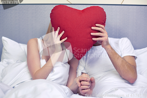 Image of happy couple in bed with red heart shape pillow
